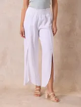 Pantalón blanco de lino con pretina ancha elastizada en punto smock, pierna ancha y ruedo con tajo.