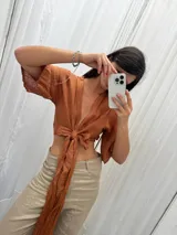 Top de lino color crudo con mangas amplias y lazo versátil para atar al frente o cruzarlo y ajustarlo atrás.