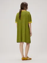 Vestido corto de algodón con estampa geométrica en tonos verde y amarillo, cuello redondo y mangas cortas con puños en color contrastante.