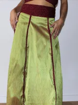 Pollera larga de satén color marrón con paneles verticales acentuados por costuras en hilo metalizado dorado. Presenta una cintura ancha de tejido elástico brillante en tono dorado.