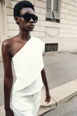 Top blanco de tejido de punto elástico, con escote asimétrico y una manga corta.