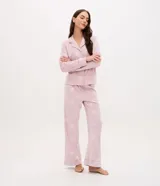 Pijama de dos piezas estilo americano confeccionado en plush suave. Incluye una camisa de manga larga con cuello en V, solapa y cierre frontal con botones, y un pantalón largo de corte recto con cintura elástica y cordón de ajuste. Presenta un estampado de lunares en toda la prenda.