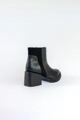 Bota corta de cuero negro con paneles laterales de gamuza y cuero texturizado. Tiene taco geométrico y punta cuadrada.