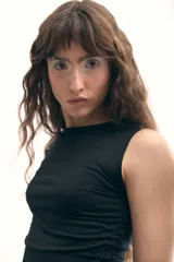 Musculosa negra con cuello redondo y corte asimétrico con jaretas laterales regulables que permiten ajustar el largo y el volumen.