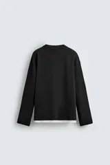 Camiseta de manga larga con corte relajado y cuello redondo. Presenta un diseño de doble capa con acabados en rib a contraste en el cuello y el ruedo.