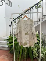 Buzo amplio de frisa liviana de algodón color gris con estampado botánico de hojas en tonos verdes. Tiene cuello redondo y tajos laterales.