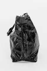 Cartera tipo tote bag de color negro con acabado brillante y efecto arrugado, cuenta con doble asa de hombro.
