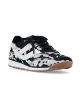 Championes urbanos con diseño de estampado animal print tipo vaca en blanco y negro, con detalles en blanco en los laterales, cordones negros y suela de goma dentada en color marrón.