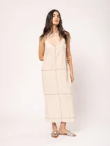 Vestido largo color crudo de lino, con silueta recta, escote en V, breteles anchos, detalle de elástico en la espalda y tajos laterales.