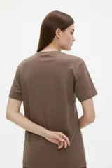 Remera de algodón color beige con estampado frontal de un corazón rosado que contiene un moño. Tiene cuello redondo y mangas cortas.