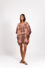 Vestido corto de silueta amplia, color tostado con bordados barrocos en contraste, escote en V con botones de madera, mangas anchas tipo capa con flecos de cuentas en los bordes.