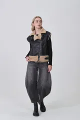 Chaleco sin mangas de cuero sintético negro con interior y detalles de piel sintética en color beige. Presenta cierre frontal asimétrico, cuello solapa y correas ajustables en la cintura.