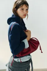 Mini bolso de hombro en color bordó con textura efecto reptil, diseño fruncido con cordones ajustables en los laterales y una sola asa superior.
