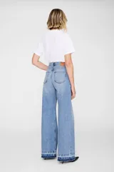 Jean de tiro alto con silueta baggy de pierna ancha, confeccionado en denim de algodón en un lavado vintage medio. Presenta diseño clásico de cinco bolsillos y ruedo al corte con efecto desgastado.