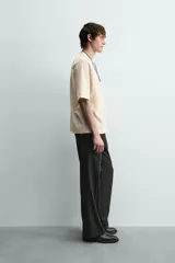 Camiseta de manga corta color crema, con cuello redondo y tejido acanalado verticalmente, de corte holgado (boxy fit).