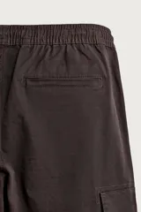 Pantalón cargo de corte ajustado en color negro, confeccionado en tejido de algodón con elasticidad. Presenta cintura elástica con cordón ajustable, bolsillos laterales tipo cargo con solapa y bajo con puños elásticos.
