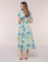 Vestido midi de gasa con estampado floral en tonos azules, verdes y amarillos, escote en V cruzado, mangas cortas con volados, cintura elastizada y bolsillos laterales.