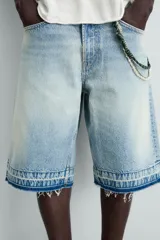 Bermuda de denim de algodón, color negro lavado, de corte ancho (baggy fit) y tiro medio. Presenta cinco bolsillos y bajo con acabado irregular deshilachado.