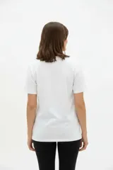 Remera de algodón blanca, de corte holgado, con cuello redondo y diseño estampado en el centro que incluye un gato comiendo de un plato y la inscripción 'Wild Cats'.
