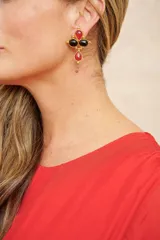 Aros colgantes con clip, con forma de cruz y detalles de piedras rojas y negras engarzadas en metal dorado.