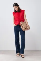 Chaleco tejido color rojo con cuello redondo, sin mangas, con desflecado en bordes y bolsillos frontales con botones dorados.