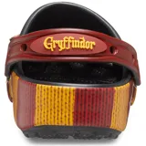Zuecos Crocs negros con suela a rayas horizontales rojas y amarillas, inspiradas en la bufanda de Gryffindor. Incluyen charms de Jibbitz de Harry Potter y el nombre de la casa Gryffindor en la tira del talón.