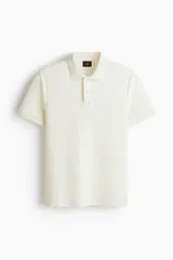 Remera polo de punto jacquard de mezcla de algodón, color blanco, de manga corta, con cuello clásico y tapeta corta de botones. Corte entallado.