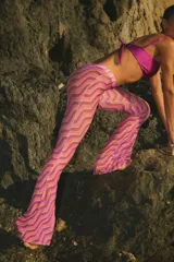 Pantalón de playa confeccionado en tul semitransparente con estampado de ondas en tonos violeta y verde lima. Presenta un corte recto y holgado con cintura elástica.