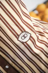 Vestido camisero corto, con cuello mao, botones a tono y parche con logo en el frente. Diseño a rayas verticales negras y blancas.