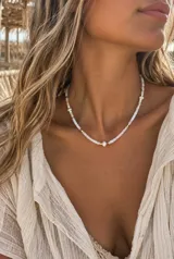Collar corto de canutillos blancos con pequeñas cuentas doradas intercaladas y perlas naturales distribuidas a lo largo de la pieza.