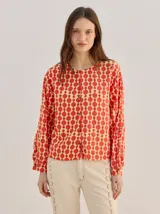 Camisa voluminosa Mutma modelo Madrana de algodón, con estampado geométrico en tonos rojo y amarillo, mangas amplias abullonadas con botones en los puños, cuello redondo y cierre frontal con botones.
