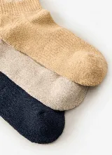 Pack de tres pares de medias de caña media con diseños estampados de la marca Rip Curl en tonos azul marino, beige y tostado.