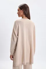 Buzo de punto oversize color beige, con cuello redondo, mangas largas y corte holgado.