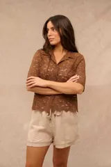 Camisa de encaje color marrón chocolate, con cuello solapa, mangas cortas y cierre frontal con botones.