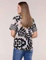 Camisa de gasa de manga corta con estampado en blanco, negro y beige, cuello con solapa, cierre frontal de botones y diseño con nudo en el ruedo.