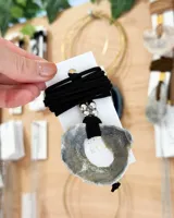 Collar con colgante de nácar irregular con orificio central, engarzado en tiento de gamuza negro con cuentas plateadas.