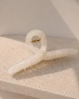 Pinza de pelo de diseño retorcido, color blanco marmolado, con resorte metálico dorado.
