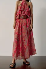 Falda larga de corte fluido con estampado paisley en tonos rojos, naranjas y celestes. Cuenta con cintura elástica y viene con un cinturón de cuero marrón con hebilla metálica dorada.