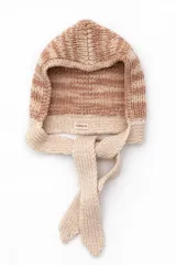 Capucha tejida a mano en lana merino con diseño de rayas horizontales en tonos beige y terracota, con lazos largos para anudar bajo el cuello.