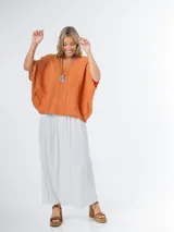 Remerón tipo poncho color naranja confeccionado en lino italiano, con escote en V y bolsillos laterales.