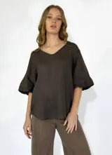 Blusa color beige de lino, con escote en V y mangas cortas acampanadas.