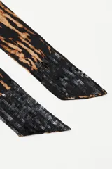 Pashmina de diseño alargado y estrecho con estampado animal print tipo cebra en tonos negro y tostado.