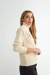 Polera de tejido de punto con cuello alto y textura acanalada en zigzag. Presenta mangas largas y puños ajustados, con un diseño clásico y versátil.