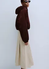 Falda midi color beige claro con diseño de tablas encontradas y corte en A.