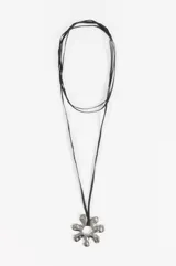 Collar largo compuesto por un cordón negro tipo gamuza y un dije central de acero con forma de flor orgánica de acabado brillante.