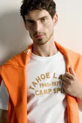 Remera blanca de corte regular fit, con cuello redondo y mangas cortas. Presenta un estampado frontal con textura en tono tostado con la inscripción "Tahoe Lake 1940-1971 Camp Sply."