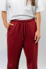 Pantalón jogger de calce relajado color bordó intenso, con cintura elastizada y lazo regulable. Cuenta con bolsillos laterales con cierre invisible y silueta recta levemente afinada.