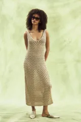 Vestido largo color beige, tejido al crochet con patrón calado. Sin mangas, con escote en V y abertura lateral.