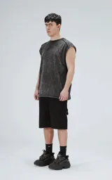 Remera sin mangas (tipo musculosa) de algodón, color negro con efecto gastado (acid wash). Presenta recortes diagonales en el frente y mangas cortas caídas, con cuello redondo.