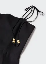 Vestido corto negro de lino con tirantes finos ajustables con lazada y detalle de abalorios.